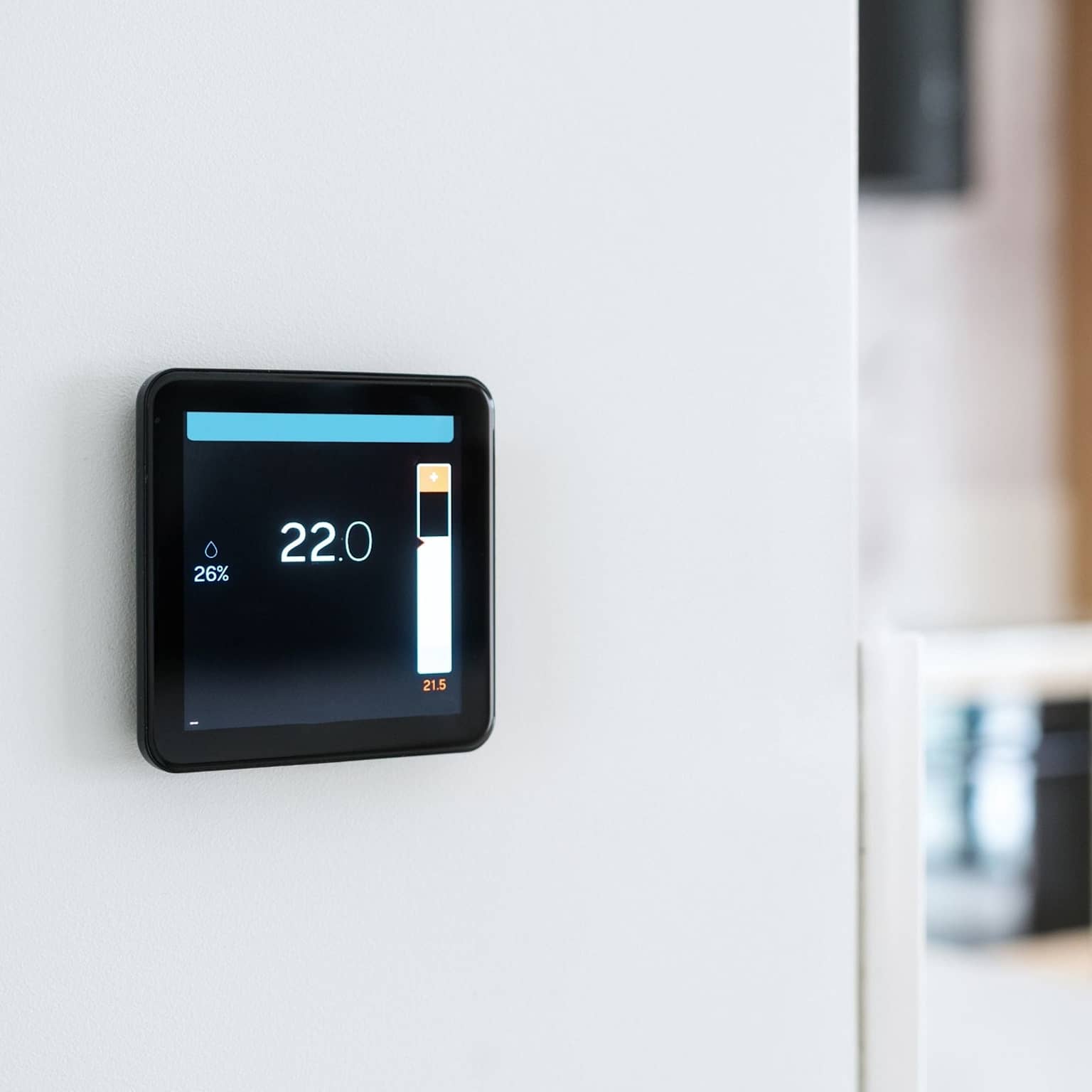 Modern wall mounted smart thermostat displaying temperature and energy saving mode