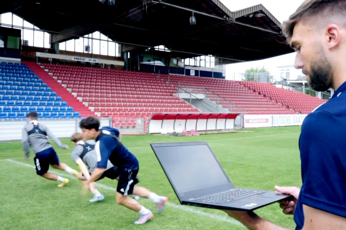 Sports analysis team on a training field using data tools