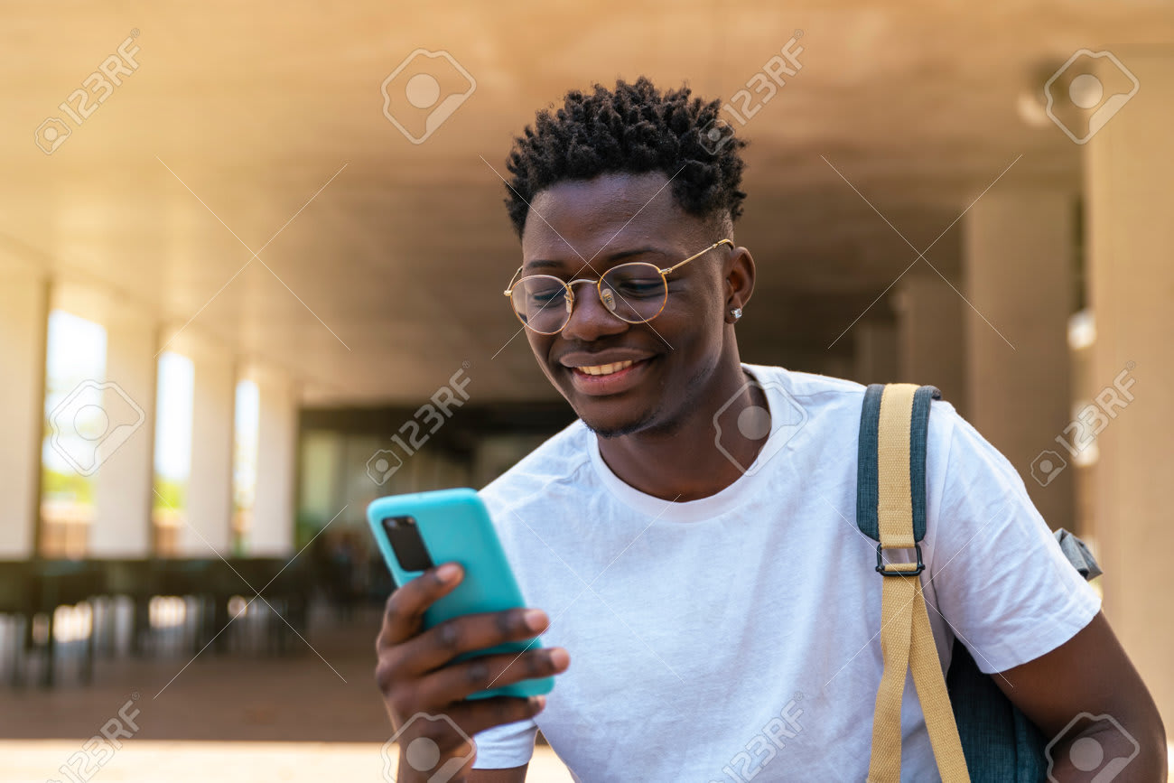 Jovem estudante sorrindo com celular na mão