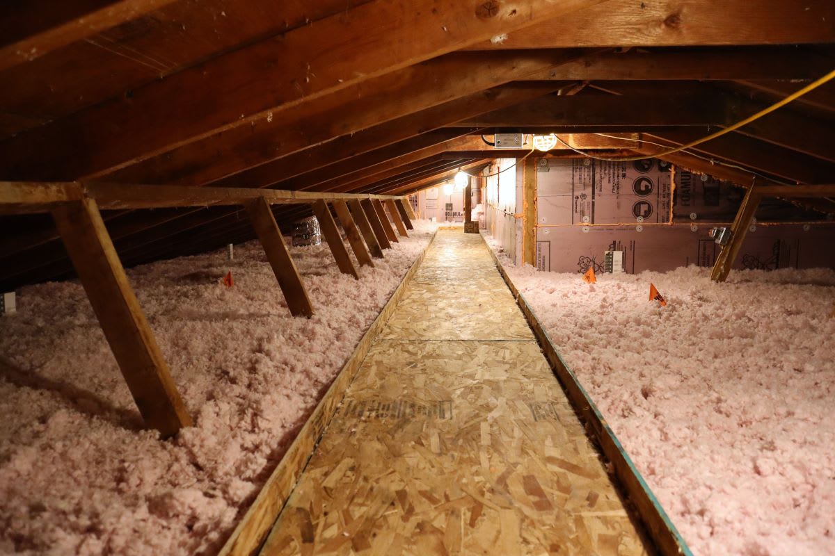 Attic floor covered in blown-in pink insulation batts for energy efficiency