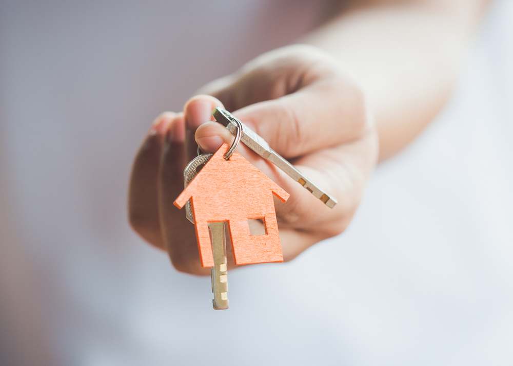 A hand holding house keys after closing