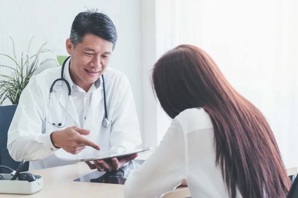 Doctor explaining cancer treatment options to a patient on a tablet