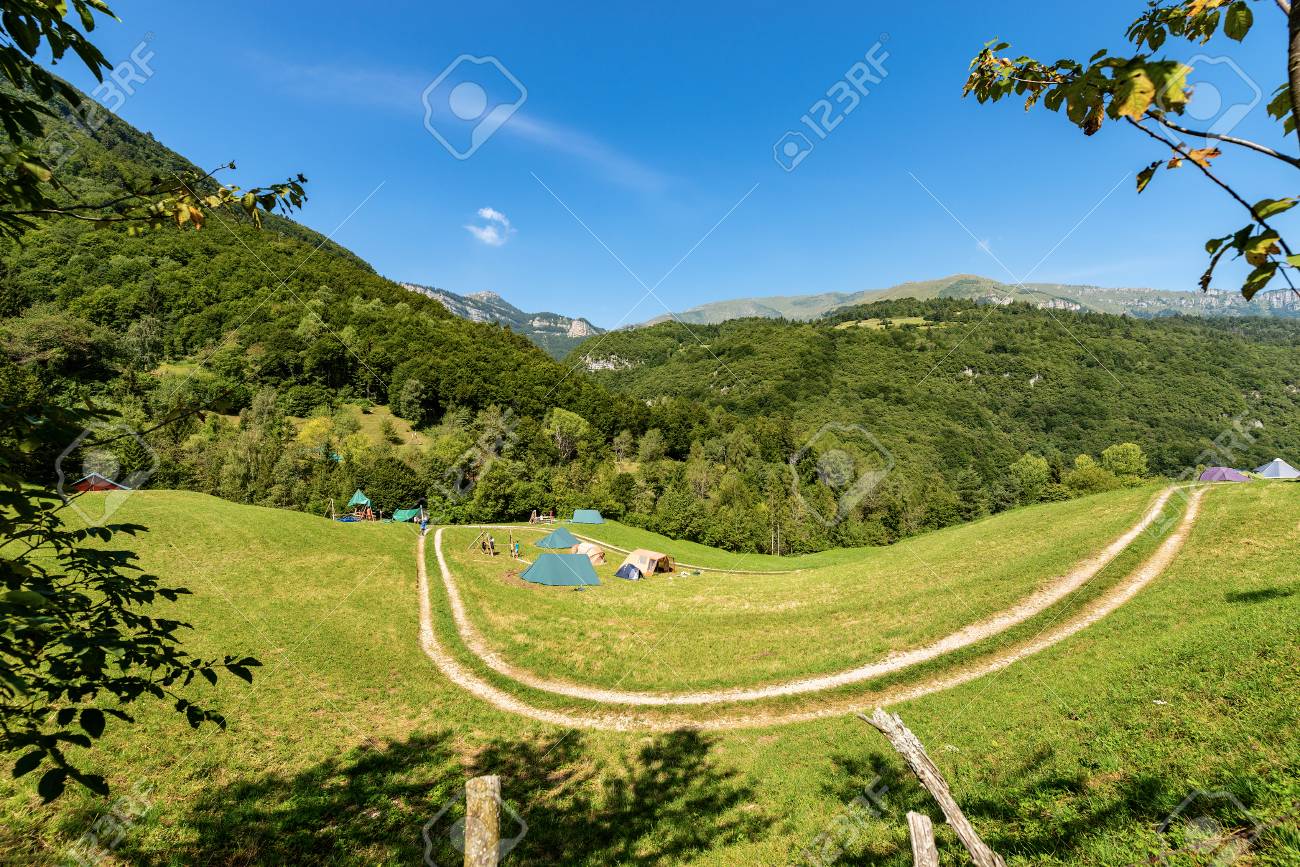 Campo scout nelle Alpi italiane con tende e boschi — zona ad alto rischio zecche
