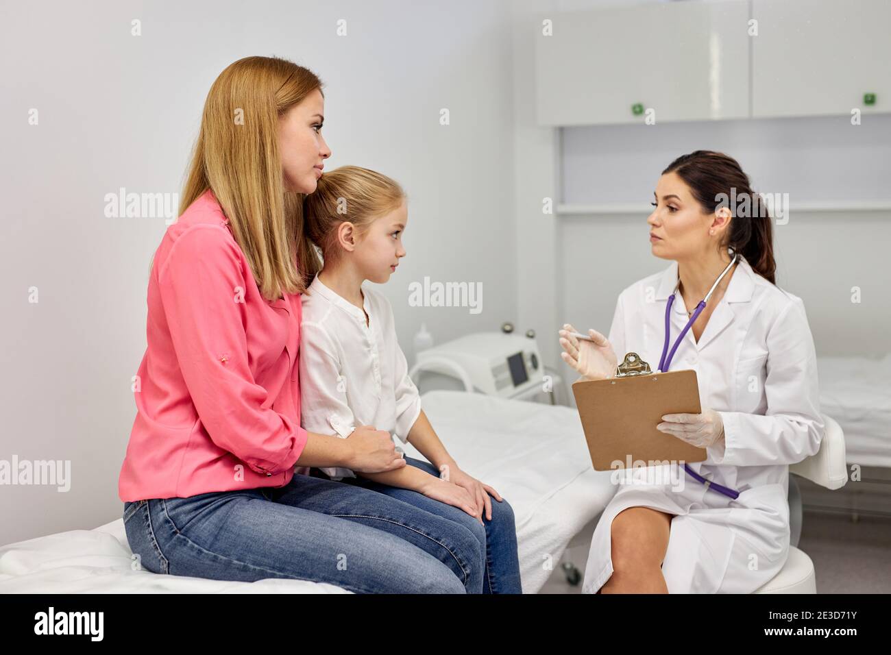 Pediatrician speaking with a child and mother in a clinic