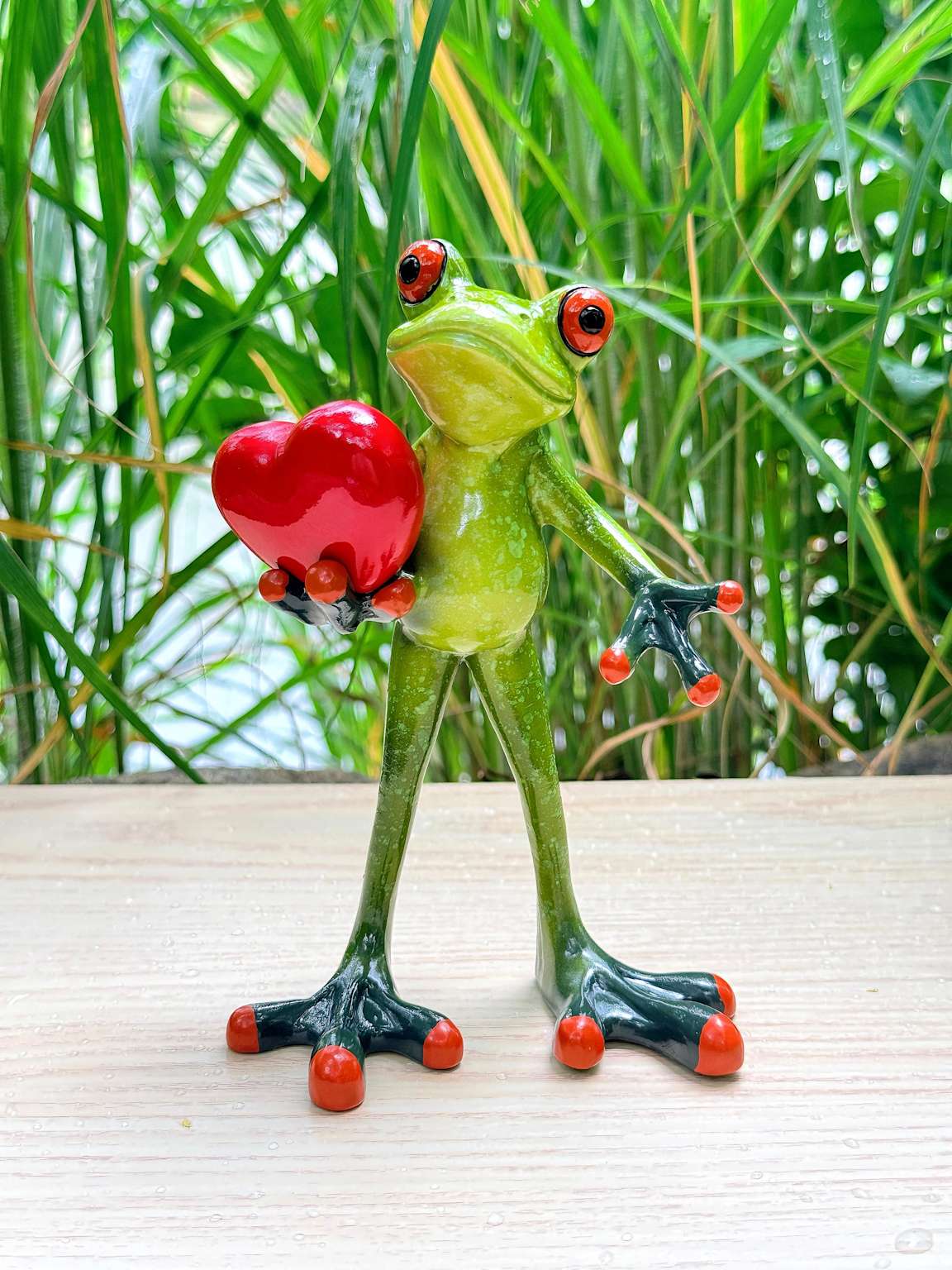 Green frog figurine holding a red heart