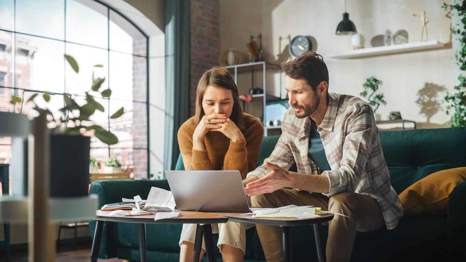 Two people discussing home buying documents with a laptop during a meeting