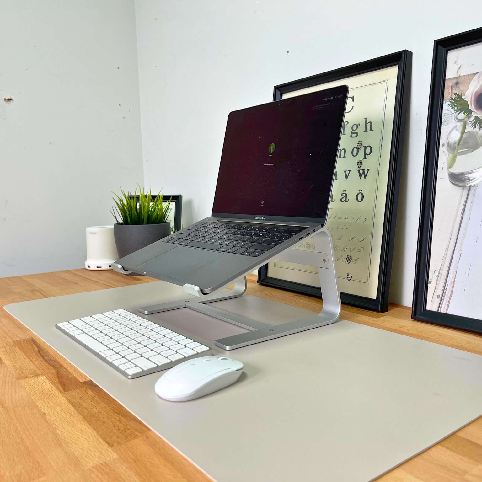 MacBook on aluminum laptop stand with wireless keyboard and mouse on a home office desk