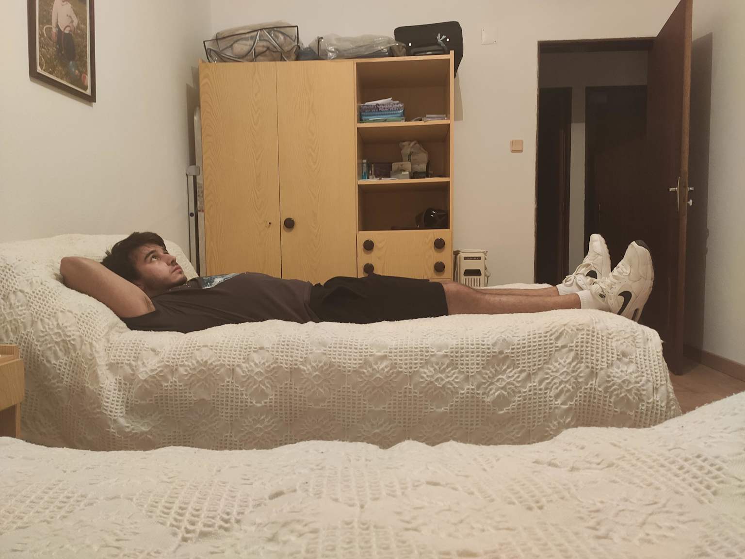 Feet hanging off the end of the bed in Nike socks