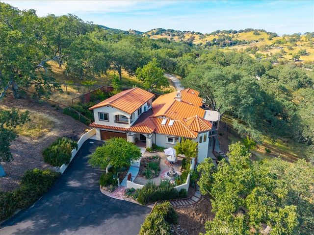 Aerial view of a house with terracotta roof surrounded by trees and hills in Atascadero