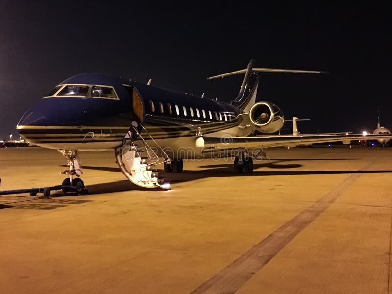 Private jet on tarmac at night with open airstairs and ground crew