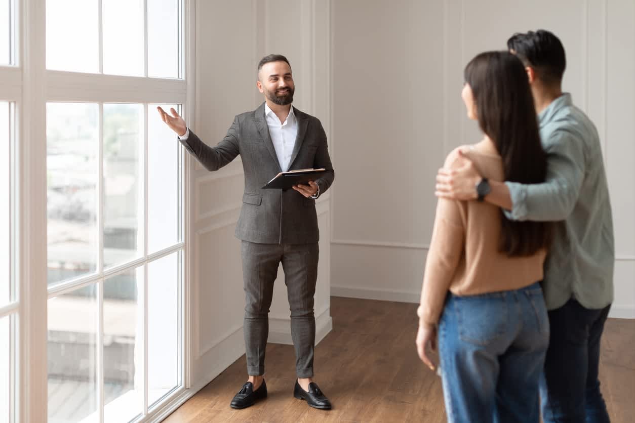 Real estate agent showing a home to a couple in a modern interior with large windows