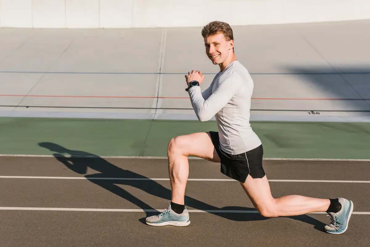 Atleta realizando exercício de avanço (lunge) em pista de atletismo, demonstrando capacidade funcional para retorno esportivo após reabilitação de joelho