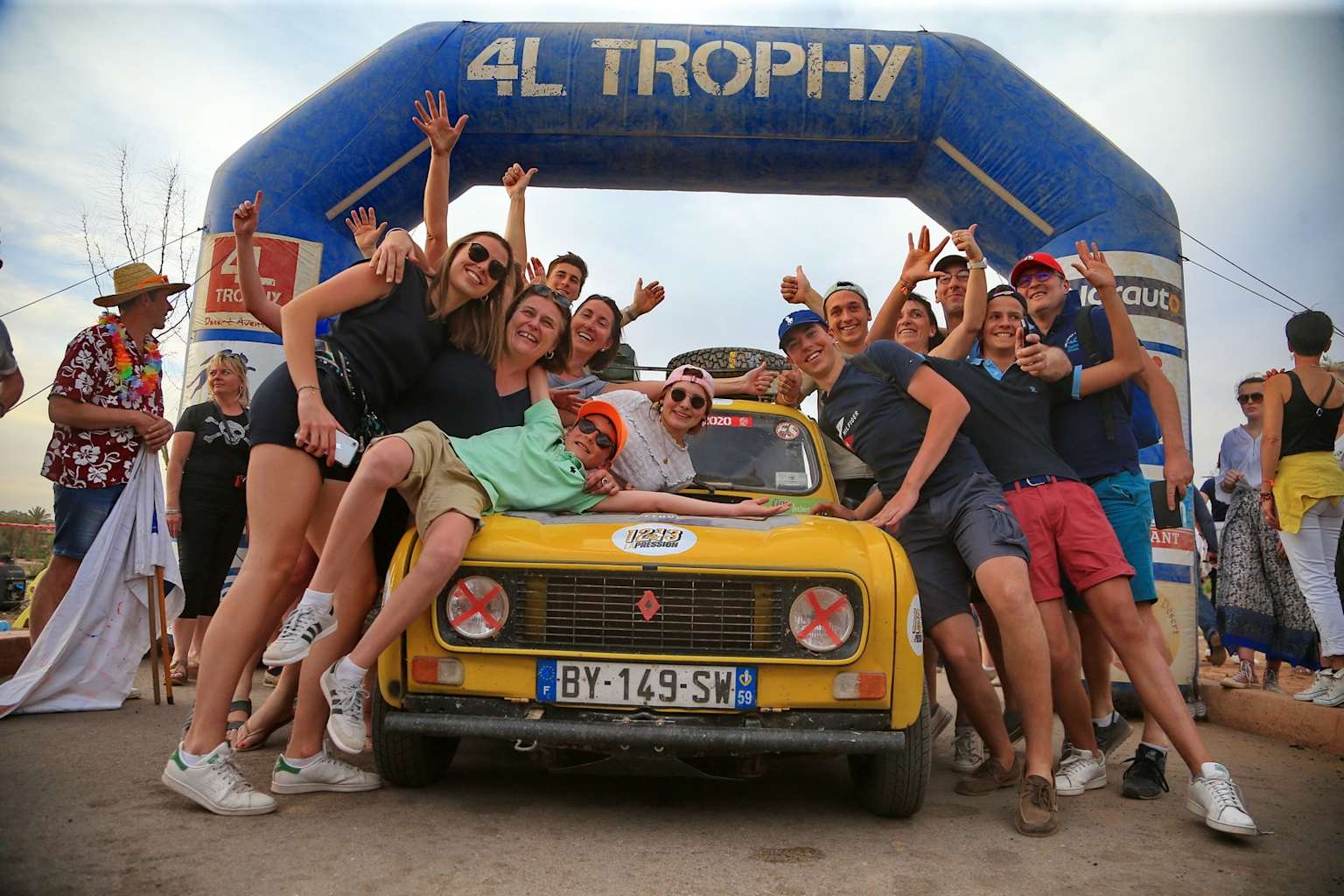 Équipe de participants fêtant l'arrivée au 4L Trophy devant une Renault 4L jaune