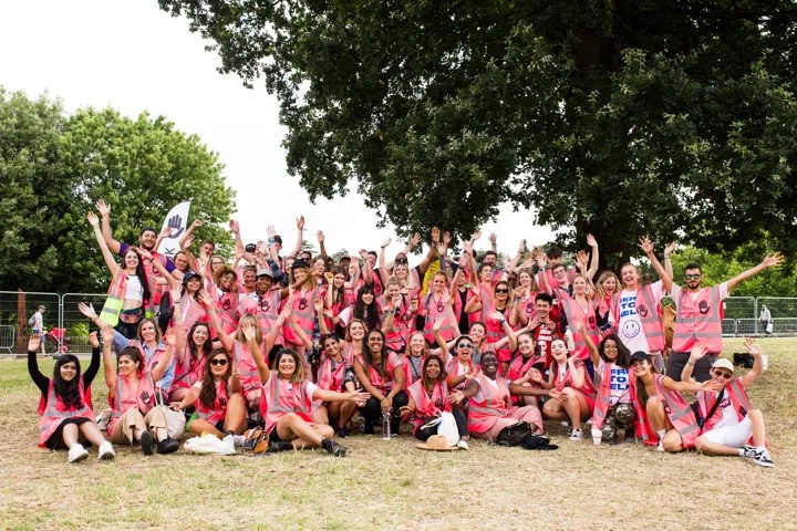 Group of festival volunteers posing outdoors on grass under trees
