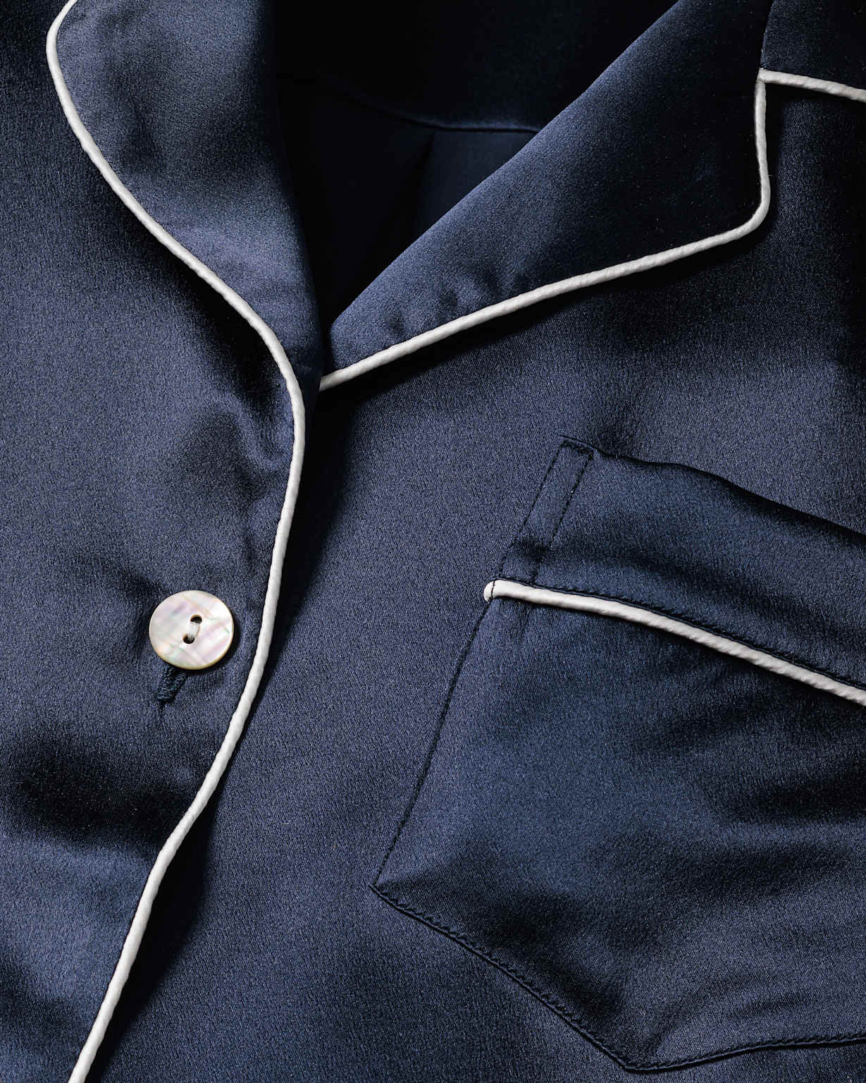 Détail d'un pyjama en soie bleu marine avec finition passepoil