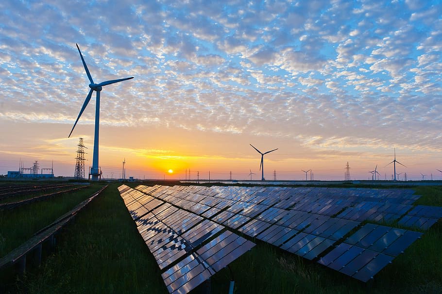 Windräder und Solarpanele auf einem Feld bei Sonnenuntergang – erneuerbare Energie für die Gemeinschaft
