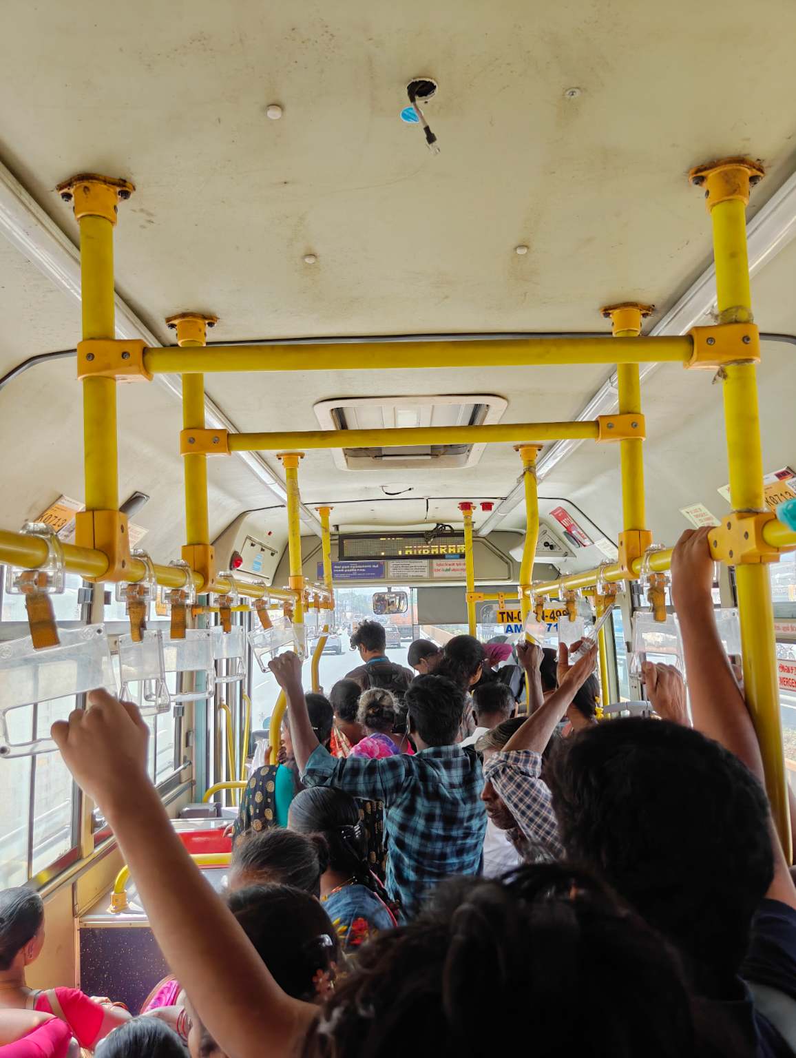 Interior of a crowded Chennai MTC low-floor bus — low ceiling for tall commuters