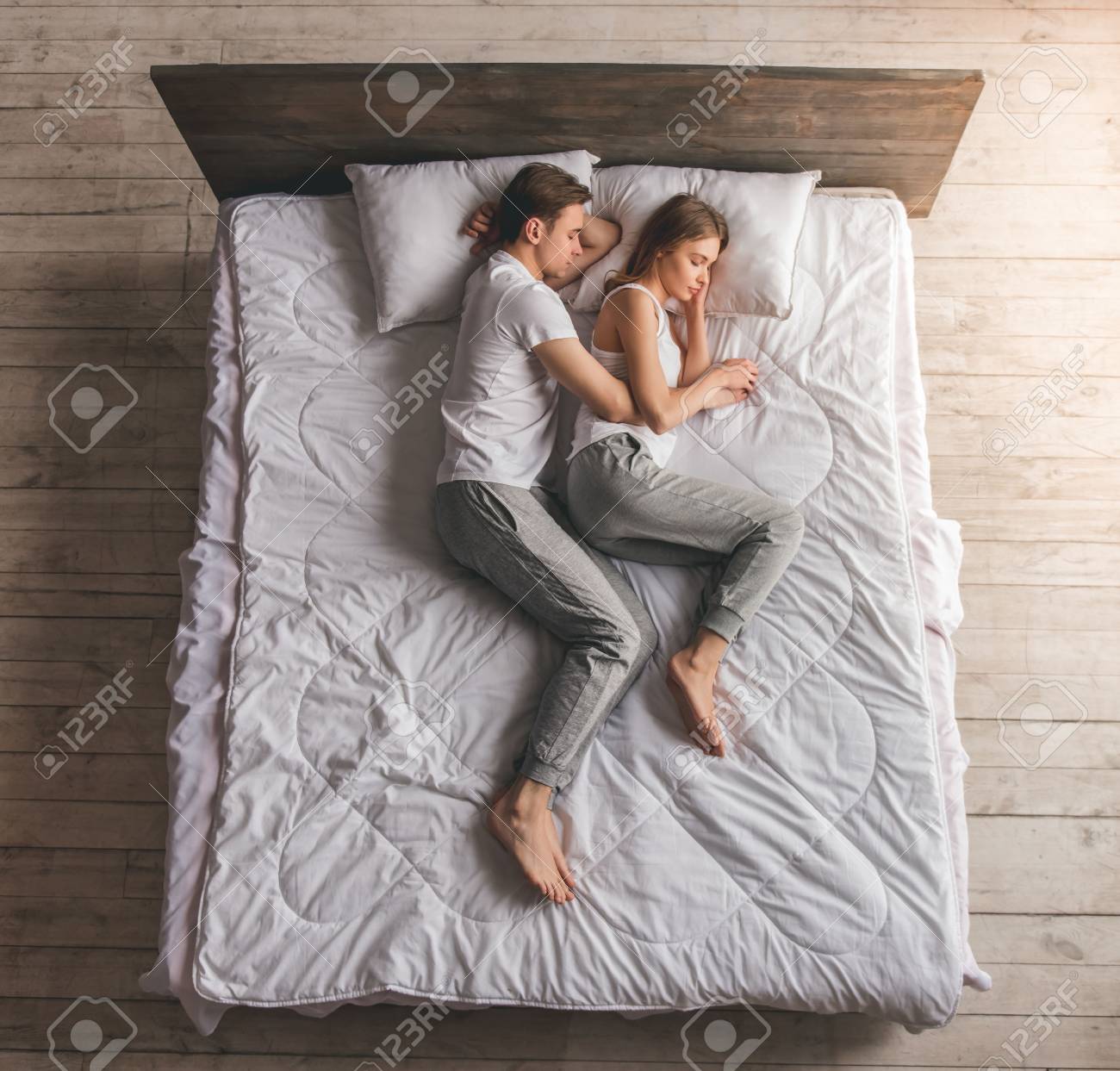 cuddling positions — couple loose embrace top view white bed