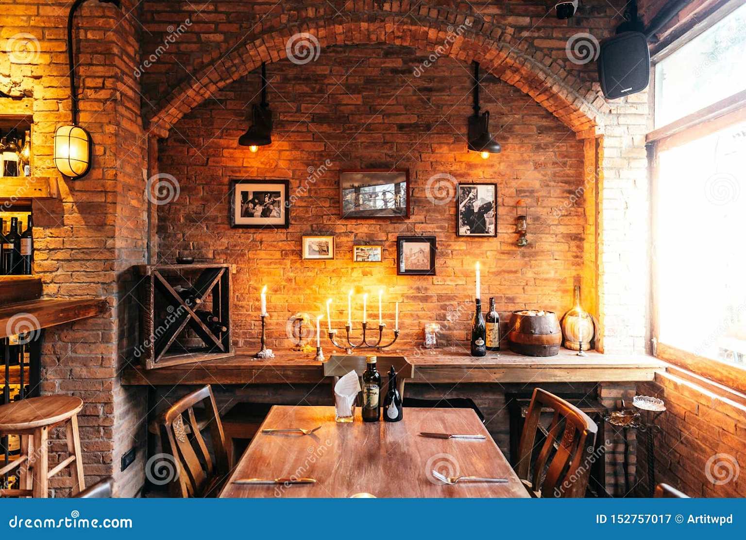 Interno dell'osteria con archi in mattoni, tavoli in legno, candele e luce calda