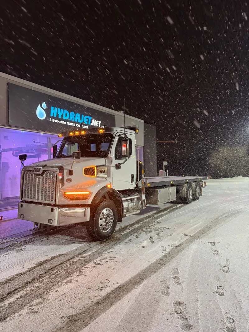 Flatbed tow truck on a snowy Ottawa road at night