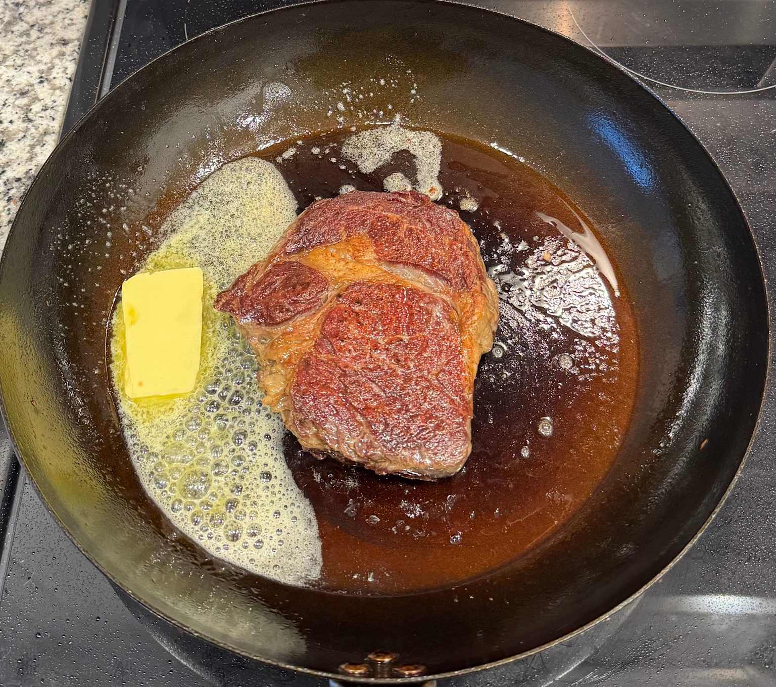 Steak searing in butter in a carbon steel pan