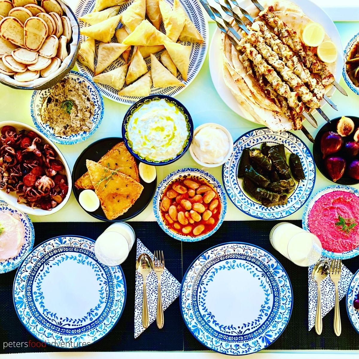 Assortment of Greek meze dishes including dips, olives, and stuffed grape leaves