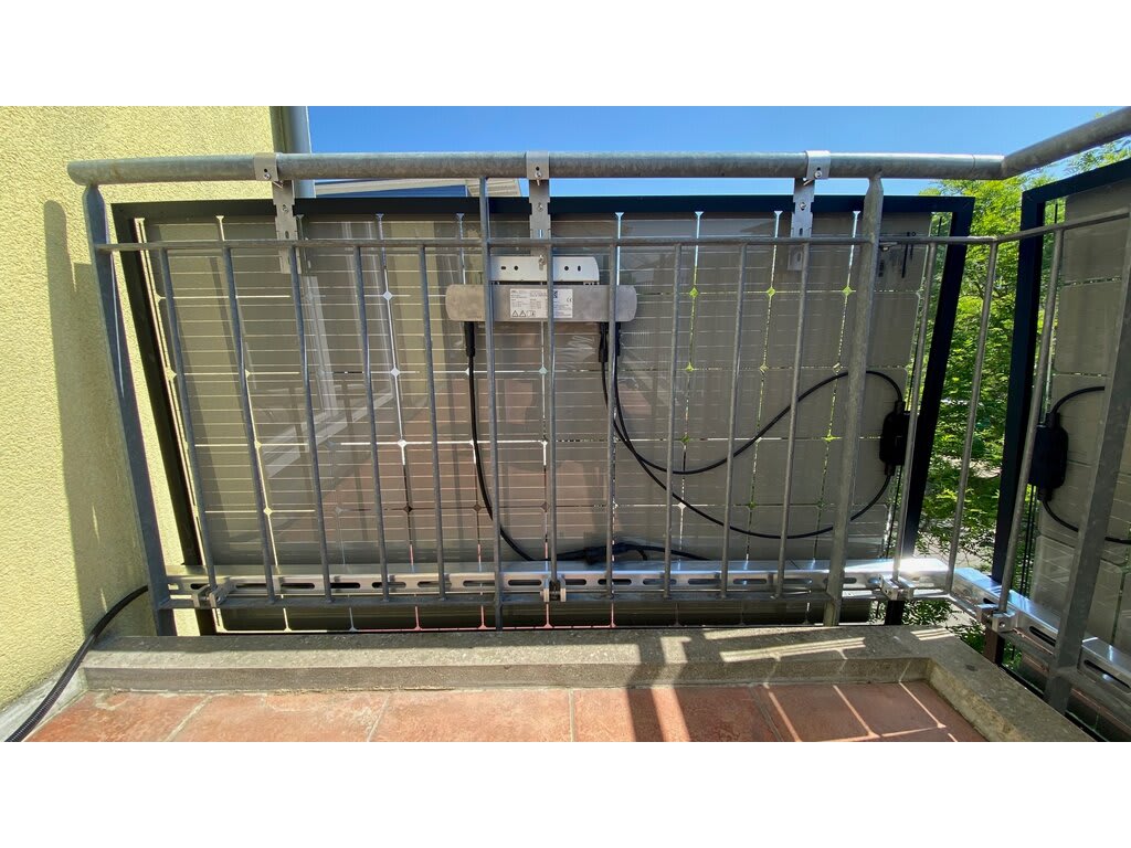 Small detachable solar panel mounted on a metal balcony railing
