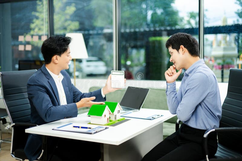 Real estate consultation in a modern office with a house model, calculator, and paperwork