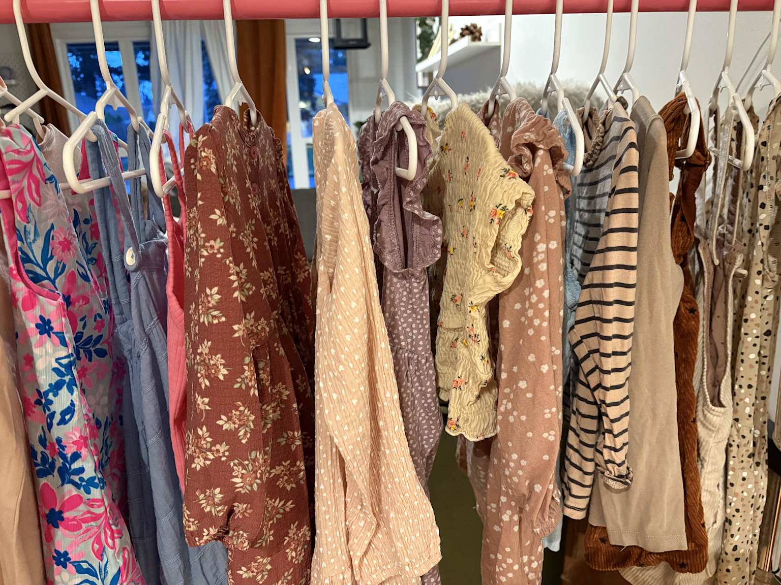 Children's dresses and tops from Zara and H&M hanging on a clothing rack