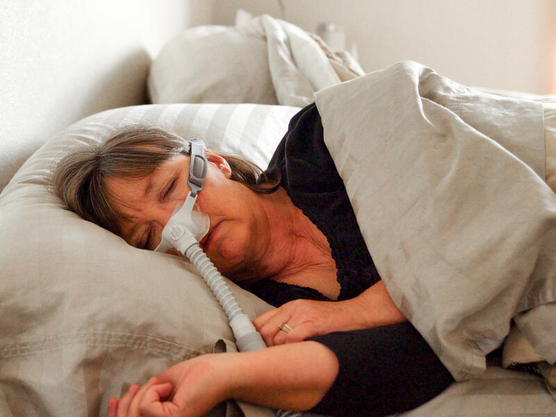Woman sleeping comfortably with CPAP machine for sleep apnea treatment