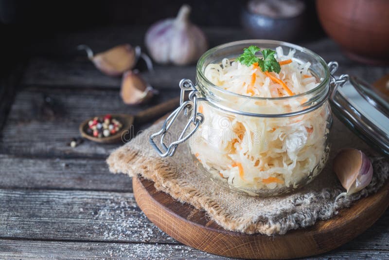 Sauerkraut im Einmachglas auf Holzbrett mit Knoblauch