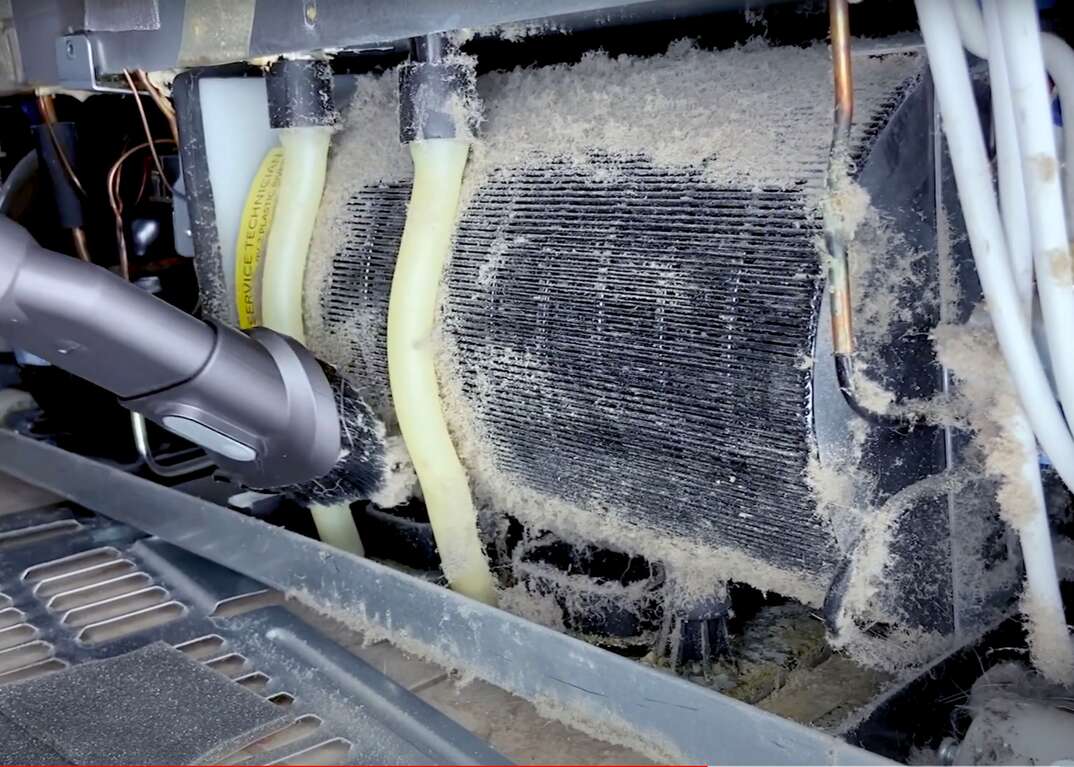 Using a vacuum to clean dirty refrigerator condenser coils