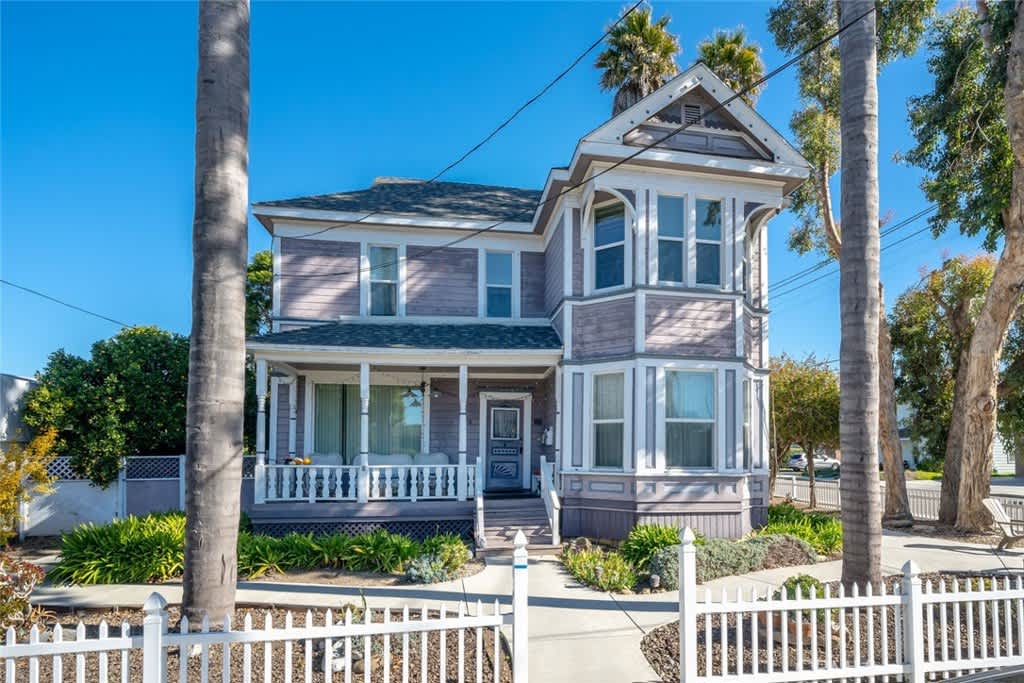 A Victorian-style Arroyo Grande home with a porch and palm trees