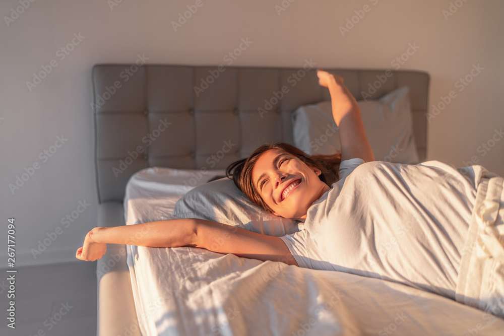 Woman waking up refreshed in the morning with sunlight streaming through window — illustrating the result of waking at the end of a natural 90-minute sleep cycle using the Wake-Up Time Calculator