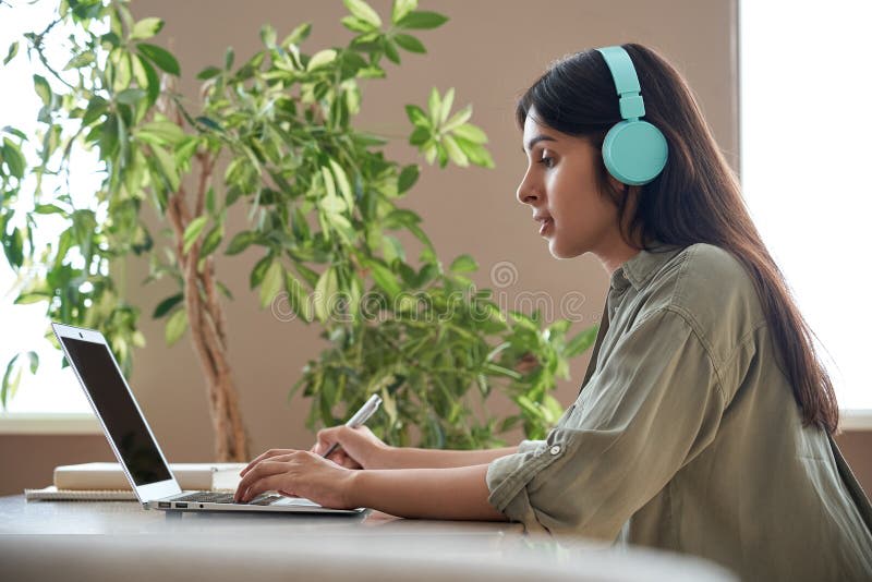 Indian student with headphones working on laptop at a study desk, representing student online jobs