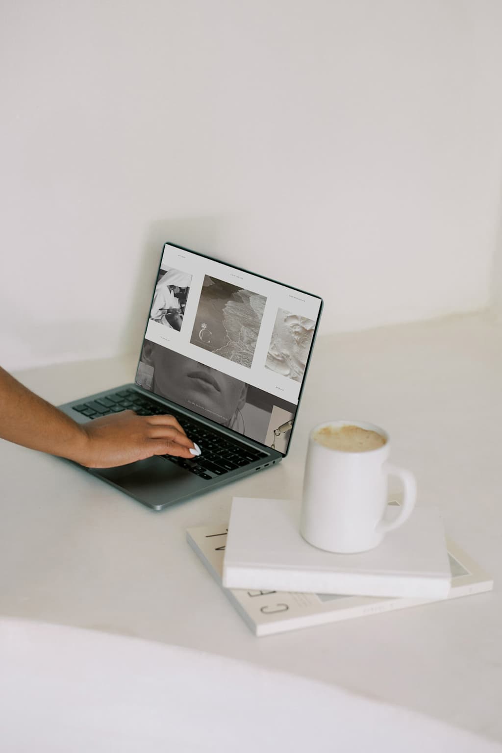 Minimal editorial desk scene with laptop, books and coffee on a clean workspace