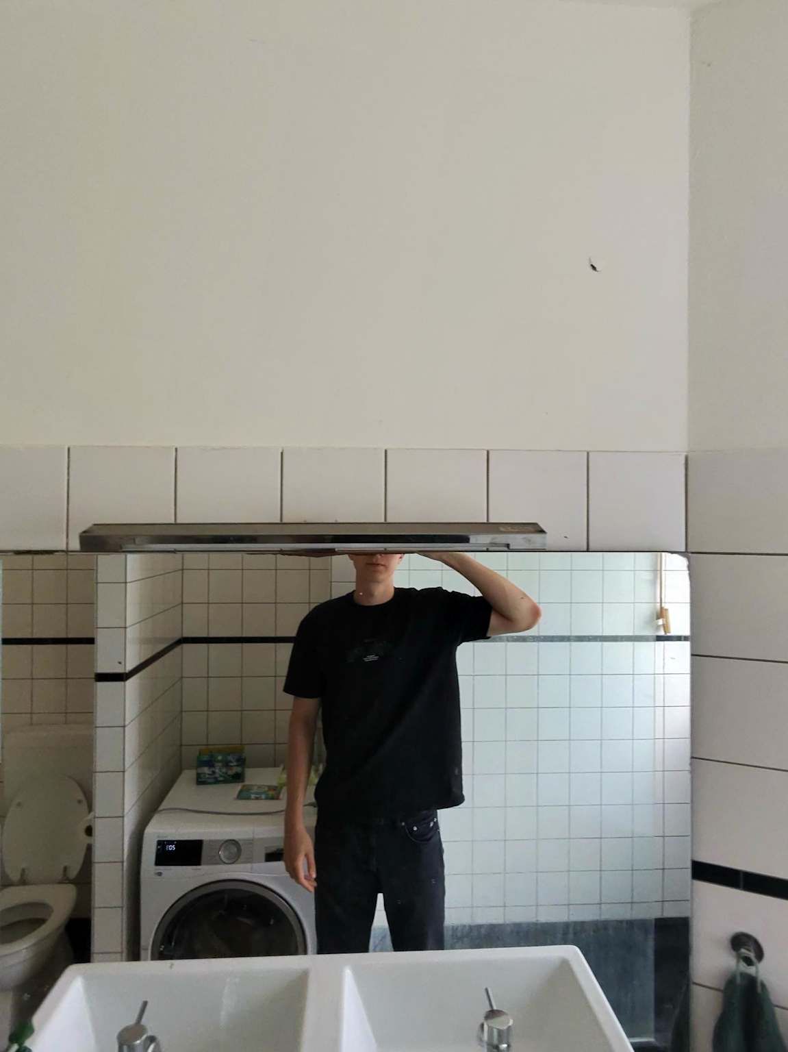 Tall person in front of bathroom mirror — head completely out of frame
