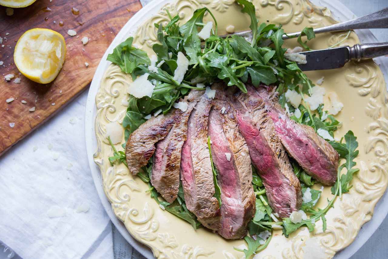 Tagliata di manzo con rucola fresca e scaglie di parmigiano su piatto