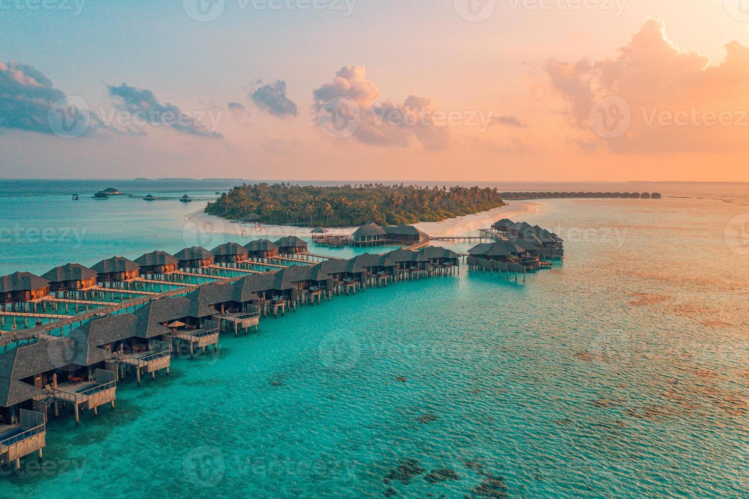 Aerial view of a Maldives island resort with turquoise water and overwater villas