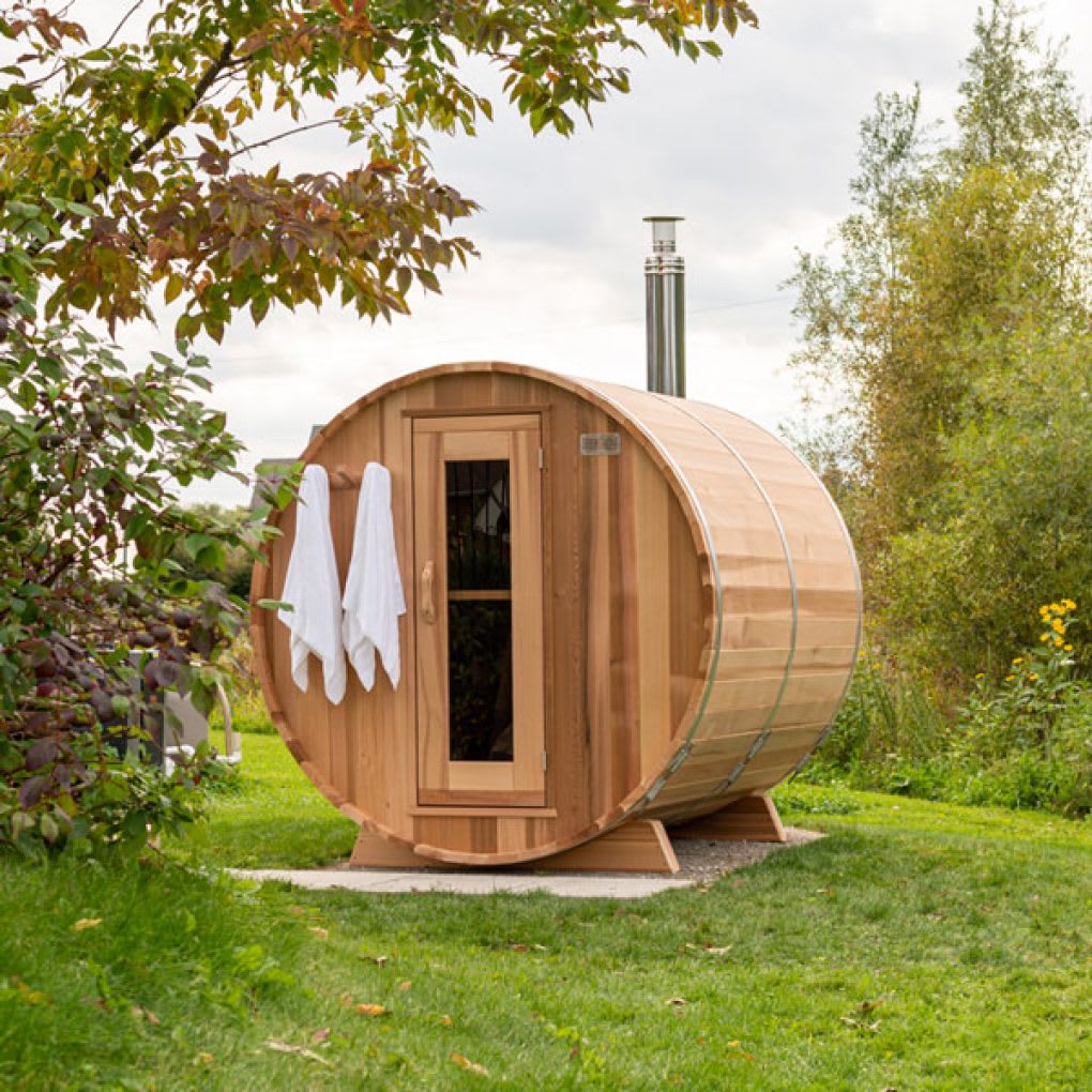 Clear cedar barrel sauna in a backyard setting surrounded by autumn trees
