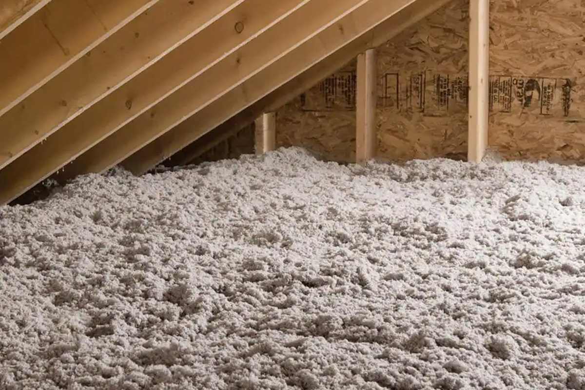 Worker blowing cellulose insulation across attic floor