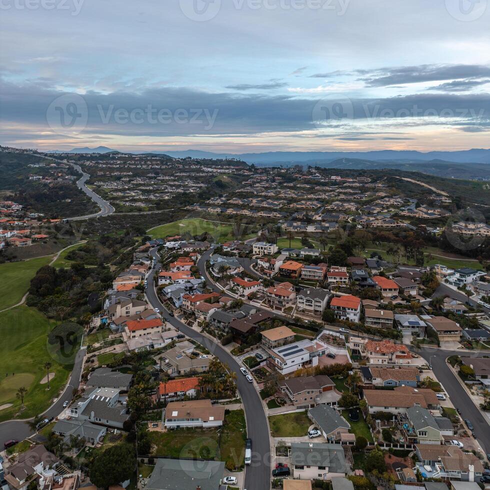 Aerial view of a coastal neighborhood with hills and the ocean in the distance