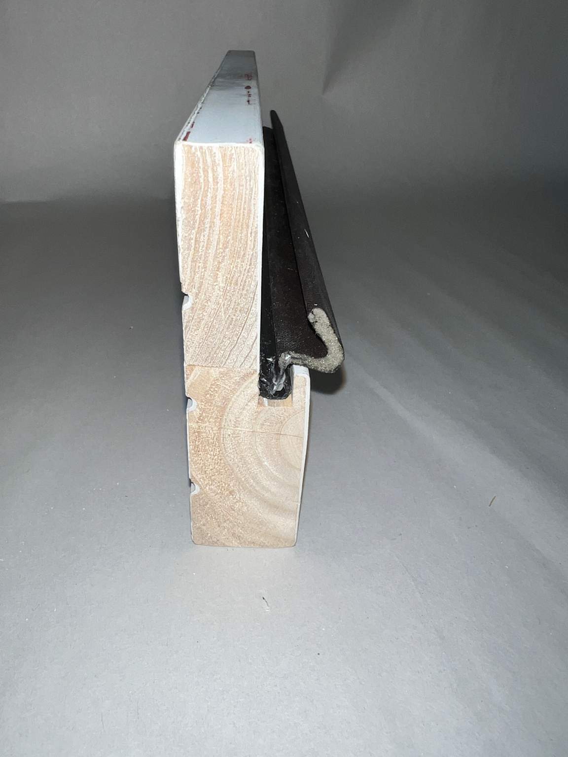 A modern wooden door frame featuring a large kerf weather stripping groove