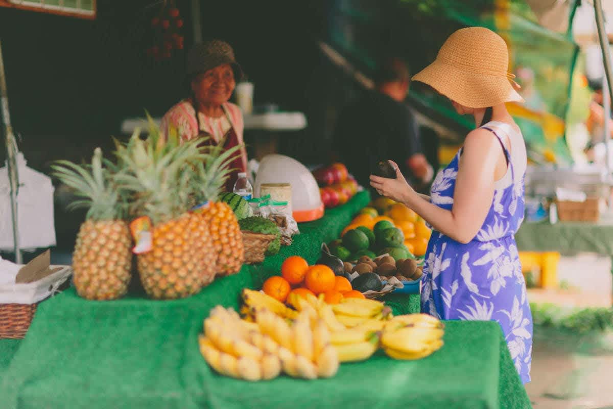 Woman browsing tropical fruit at an Oahu farmers market