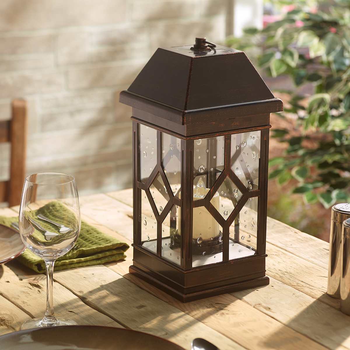 Outdoor solar lantern placed on a patio table with wine glasses