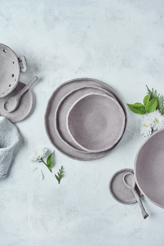 Assorted ceramic bowls and plates arranged on a light textured surface