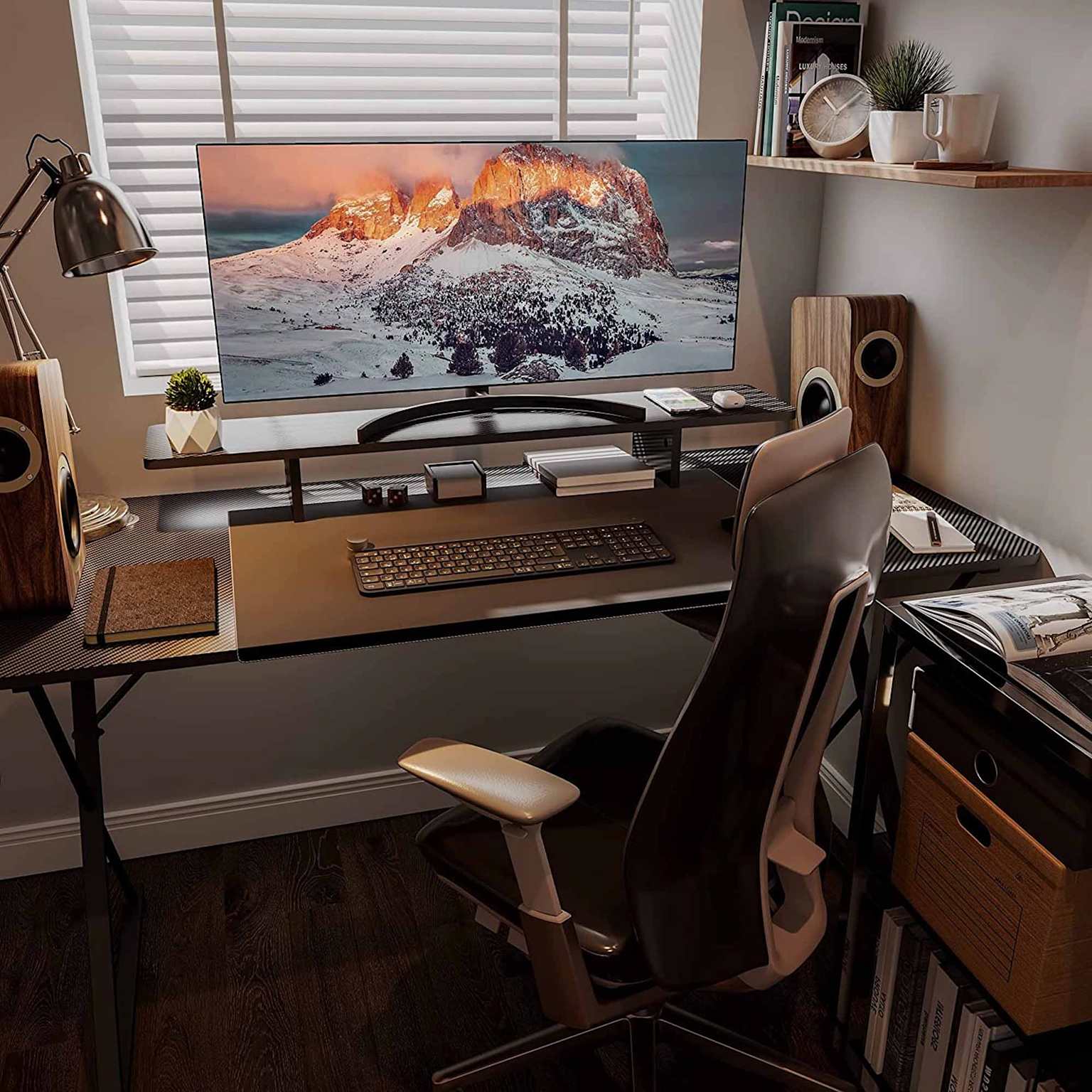 Clean, organized desk setup with monitor stand, books, plants, and minimal surface clutter