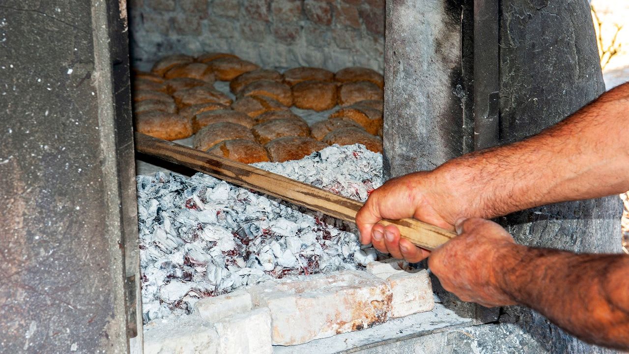 Αρτοποιός δουλεύει στον παραδοσιακό ξυλόφουρνο