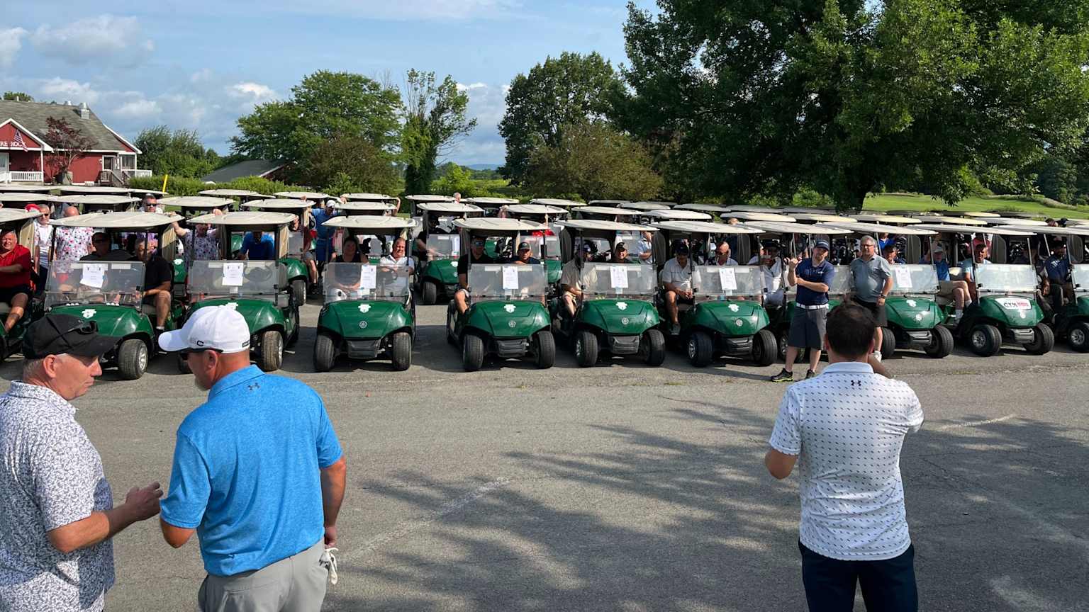 Golfers at a charity tournament gathering near carts before play