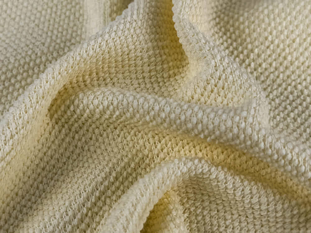 Cotton pique knit fabric texture close up showing honeycomb pattern